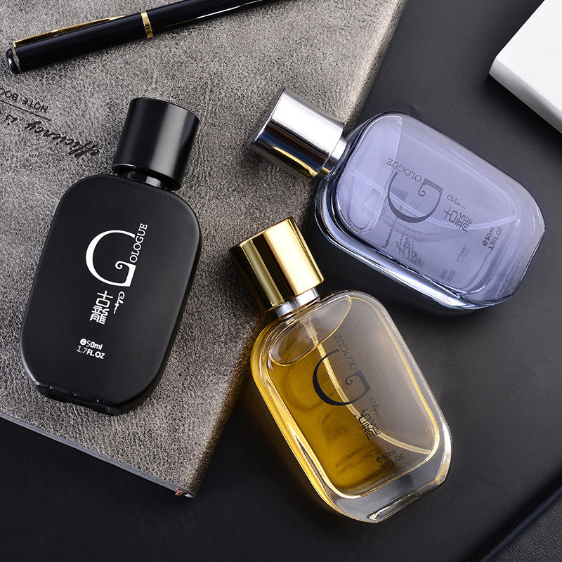 Three rounded cologne bottles in black, gold and grey arranged on a leather notebook